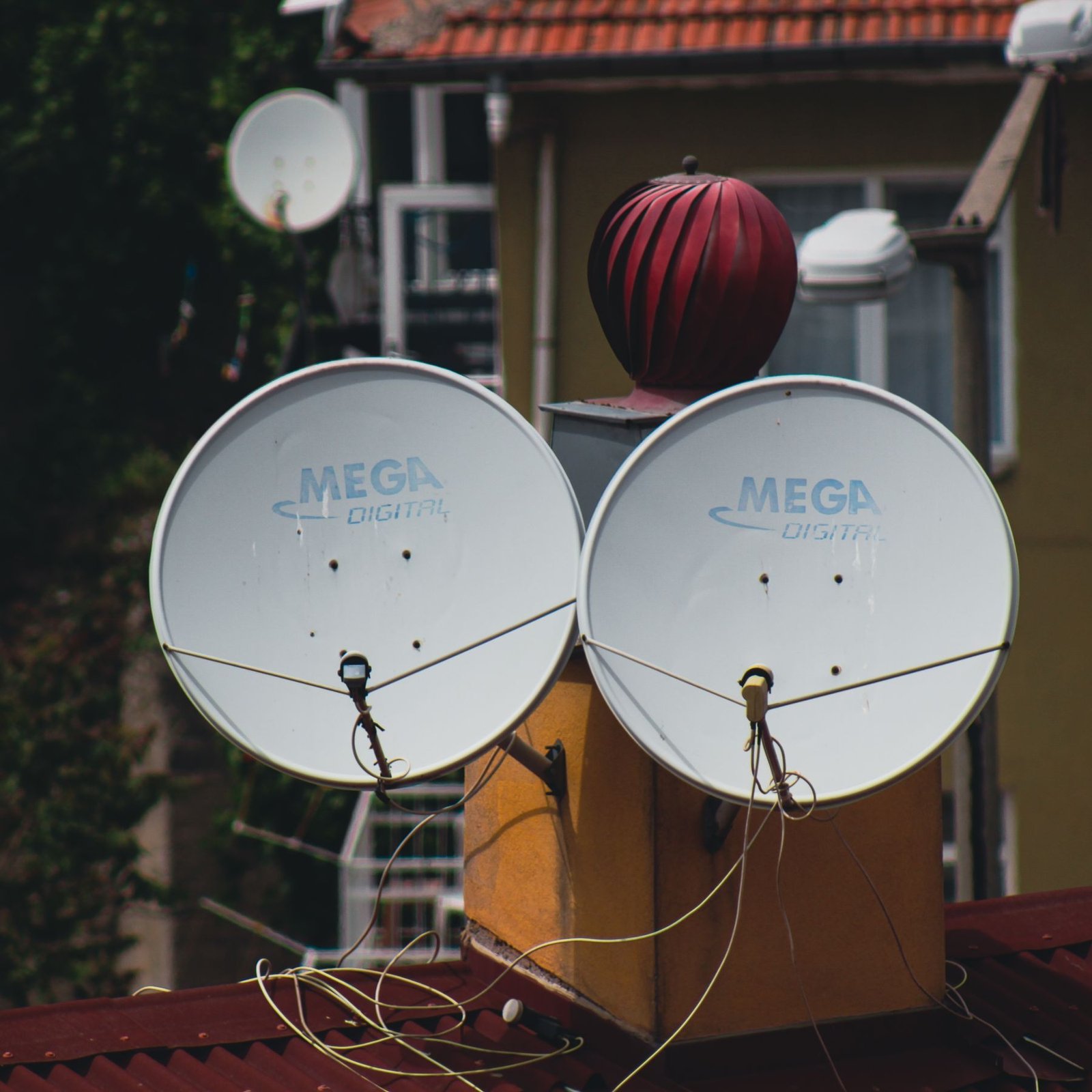 Two DTH satellite dishes mounted on the outside wall of a house