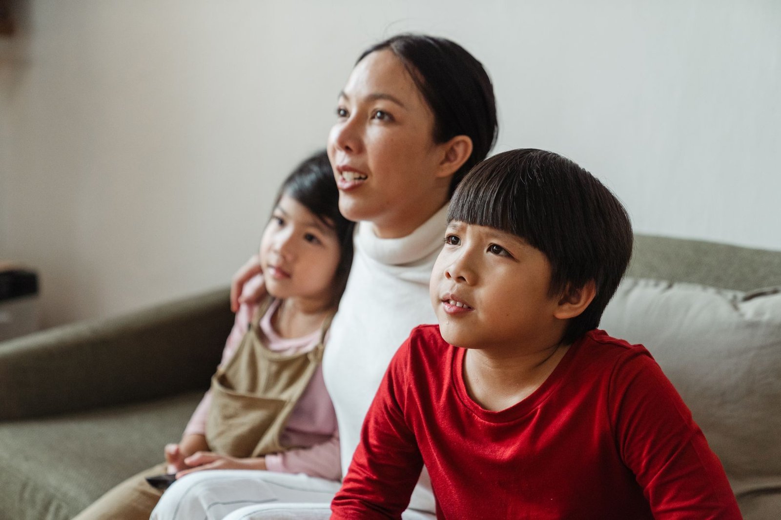 Mother and two children watching television together at home